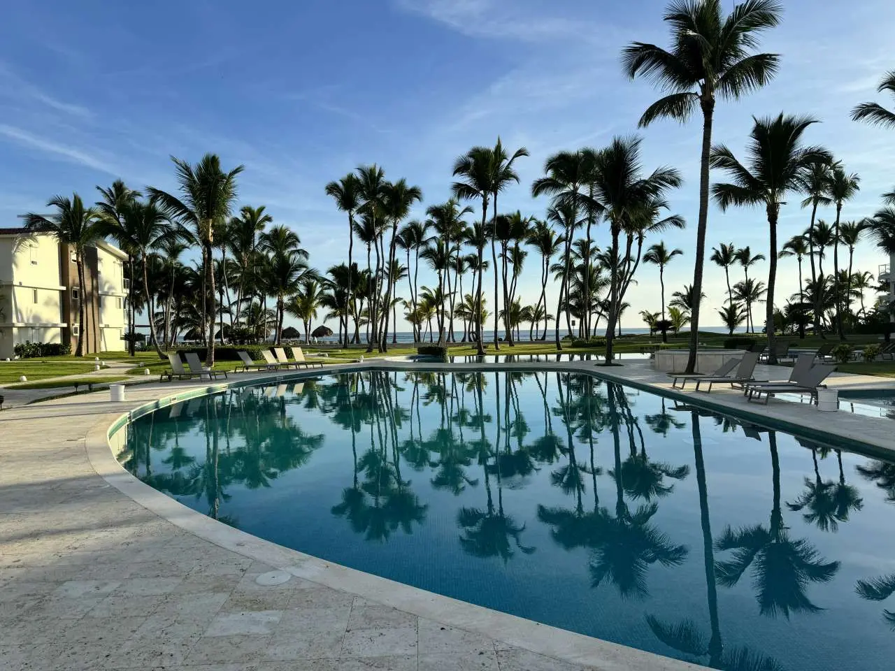 View from Ocean View Apartments overlooking the pool, palm trees reflected in the water surface and private beach